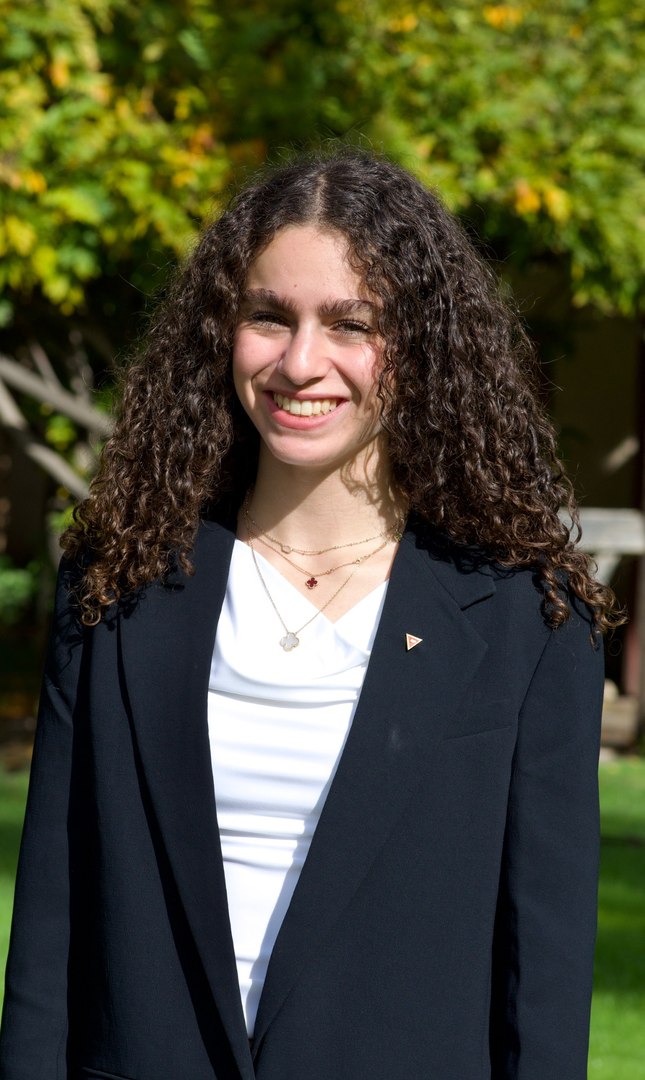 Norah Mehanna smiling outdoors in a blazer.
